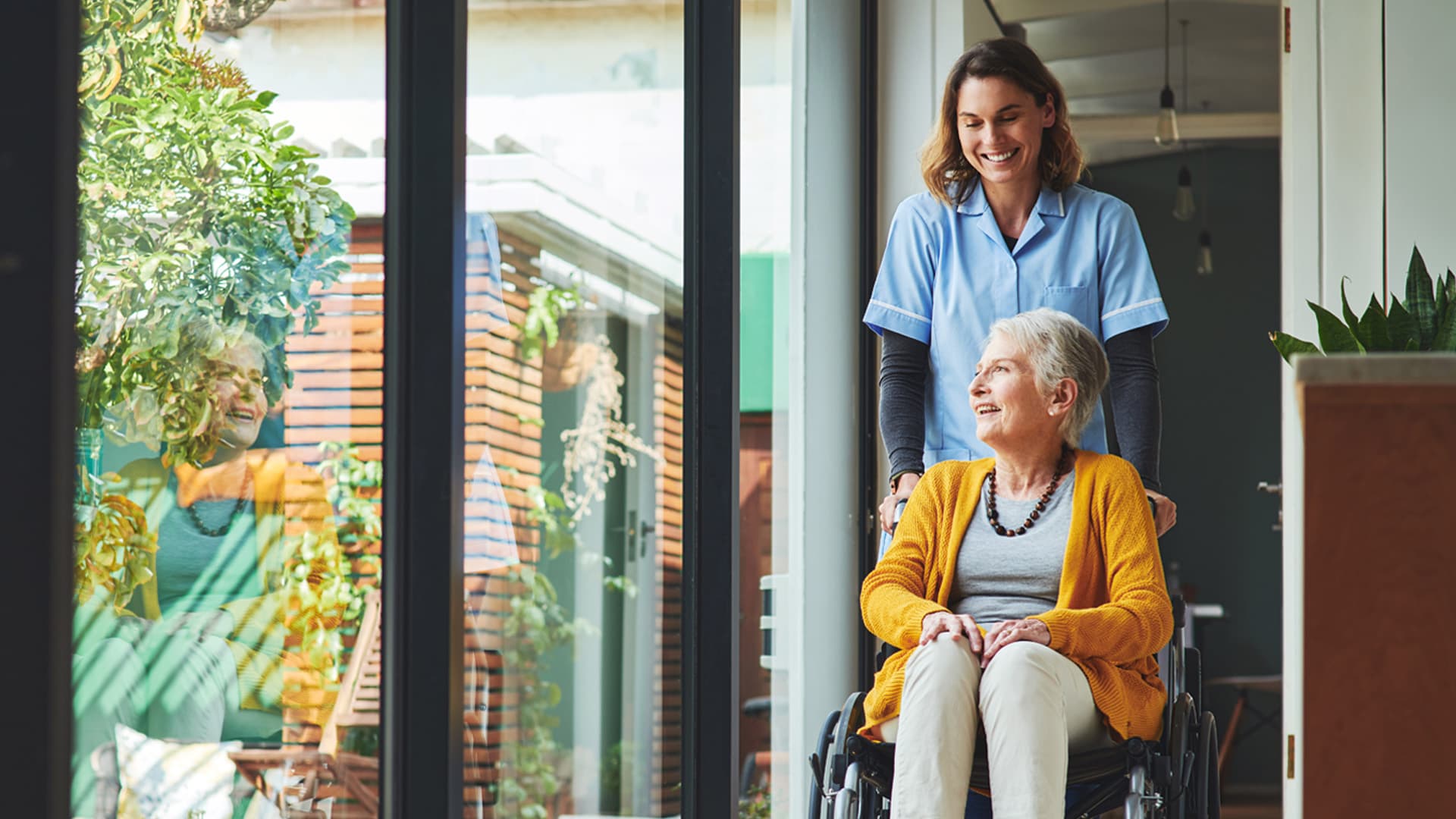 Pflegerin mit Patientin im Rollstuhl in Pflegeheim